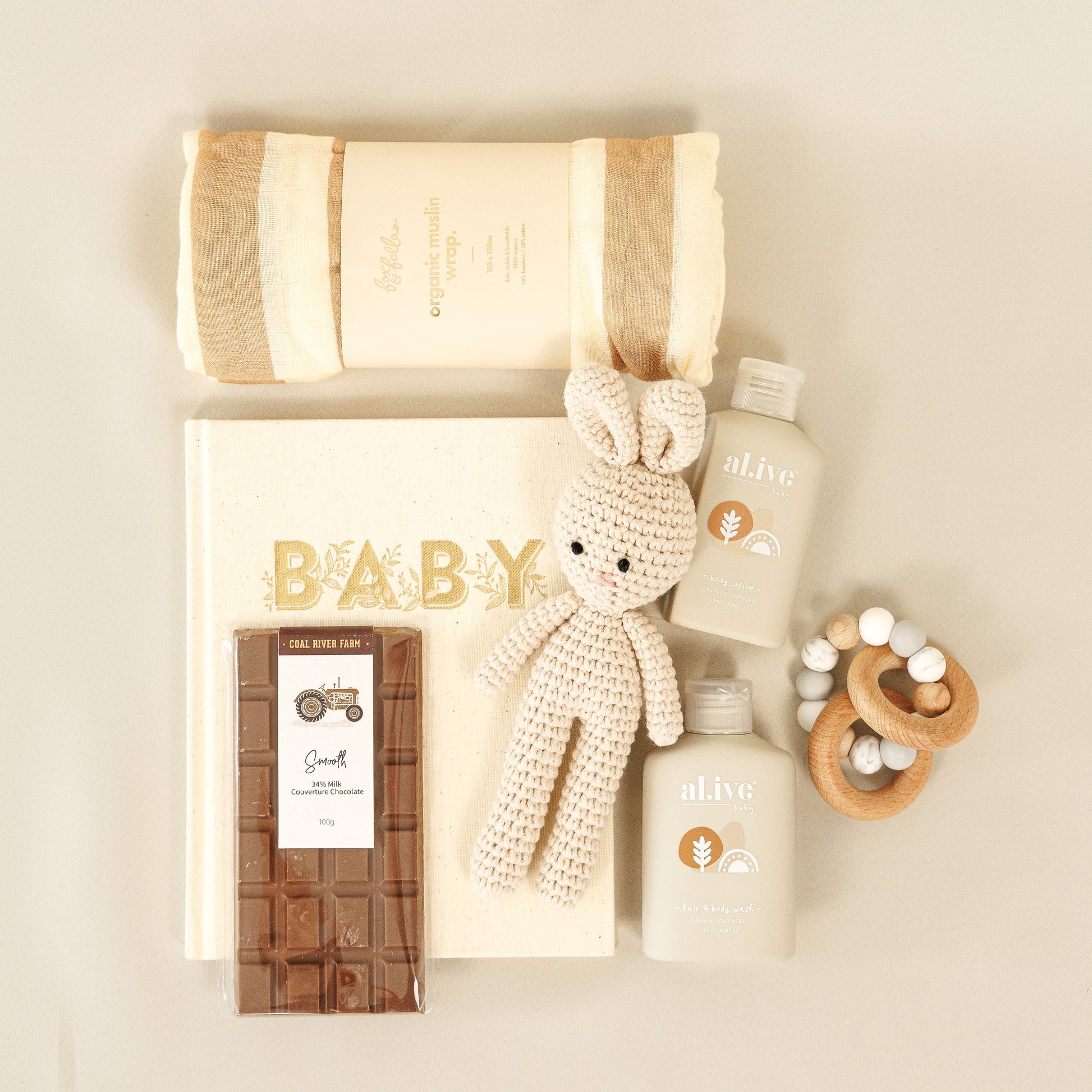 Baby gift set with items including a blanket, toy, and bottles on a beige background